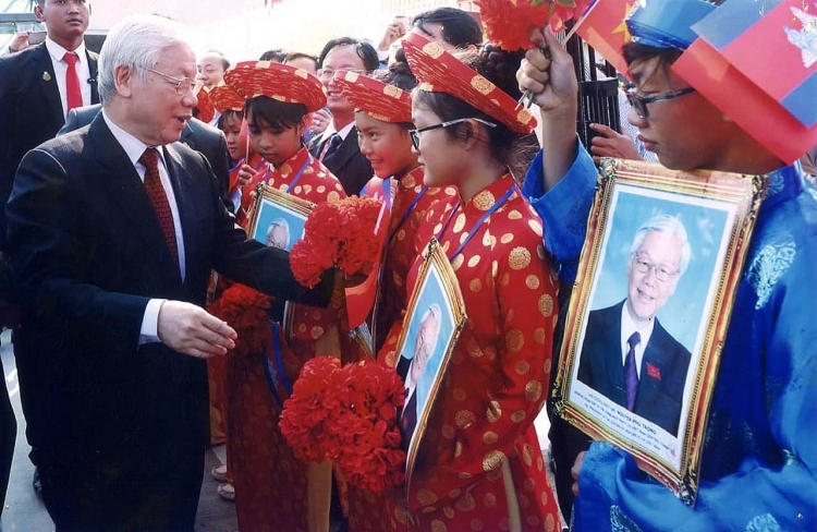 Tổng Bí thư Nguyễn Phú Trọng hỏi thăm các cháu thiếu nhi là con em người gốc Việt Nam tại Campuchia. (Ảnh: Hội Khmer - Việt Nam tại Campuchia)  ທ່ານ​ເລ​ຂາ​ທິ​ການ​ໃຫຍ່ ຫງວຽນ​ຟູ​ຈ້ອງ ຖາມຂ່າວ​ເດັກ​ນ້ອຍ​ຊາວ​ຫວຽດ​ນາມ ຢູ່ ກຳ​ປູ​ເຈຍ. (ພາບ: ສະມາຄົມຂະເໝນ-ຫວຽດນາມ ຢູ່ ກໍາປູເຈຍ)