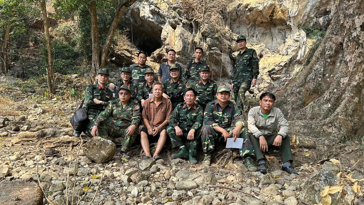 Đoàn khảo sát chụp ảnh trước cửa hang Kho K5 trong chuyến công tác hồi cuối tháng 3 đầu tháng 4/2023. (Ảnh: Vũ Trình Tường) ທີມງານສຳຫຼວດໄດ້ຖ່າຍຮູບຢູ່ໜ້າຖ້ຳຄໍ K5 ໃນລະຫວ່າງ ການເດີນທາງໄປປະຕິບັດງານ ໃນທ້າຍເດືອນມີນາ ແລະ ຕົ້ນເດືອນເມສາ 2023. (ພາບ: ວູ້ຈິງເຈືອງ)